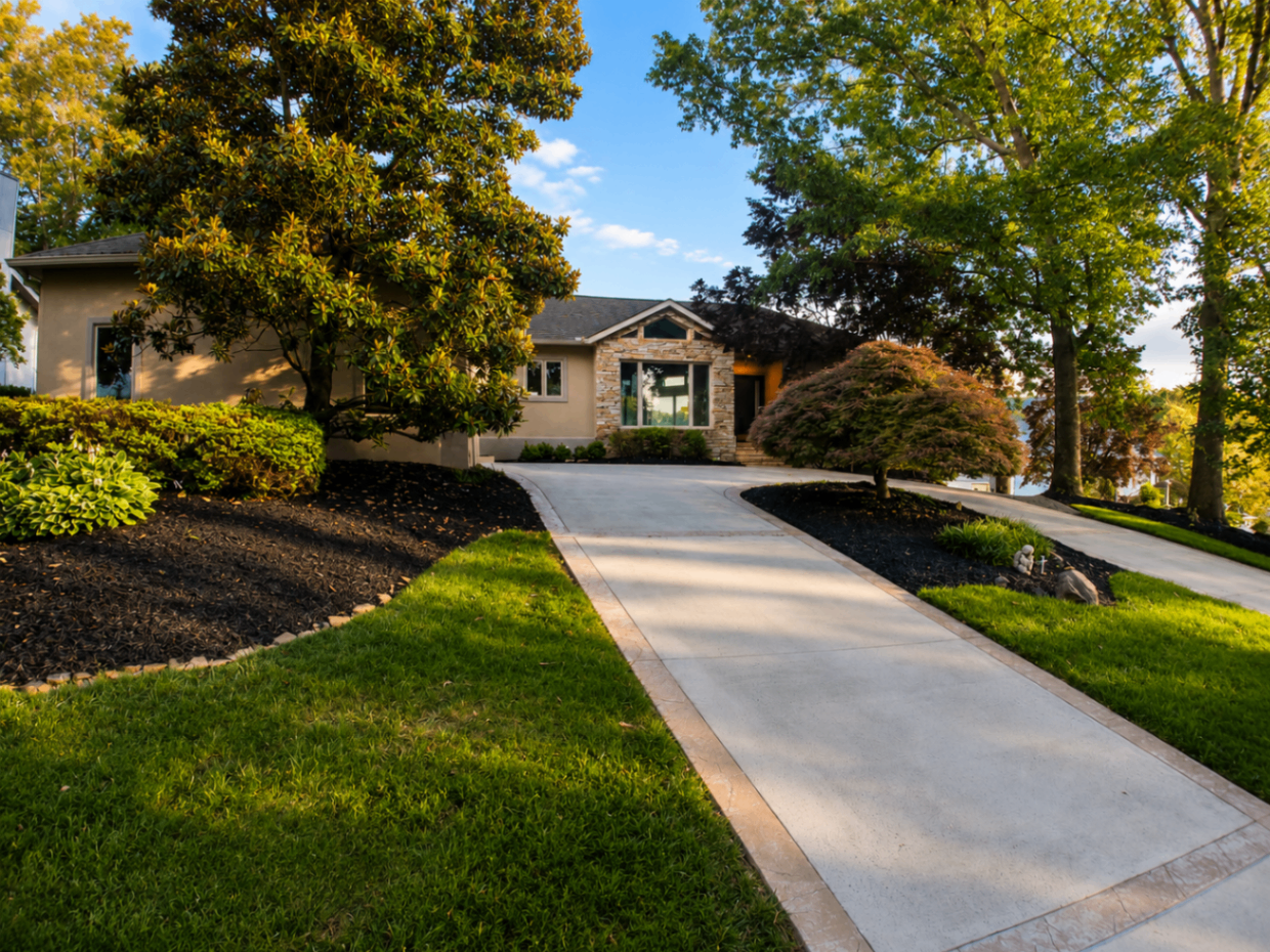 Manicured front yard with stone-accented ranch home and curved driveway
